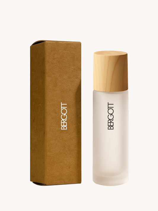 A wooden cap frosted glass bottle with 10ml of oil alongside its brown cardboard box with branding